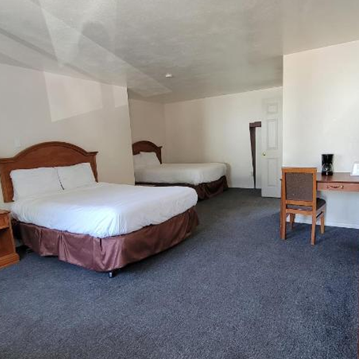 Photo of a hotel room with beds and a desk.